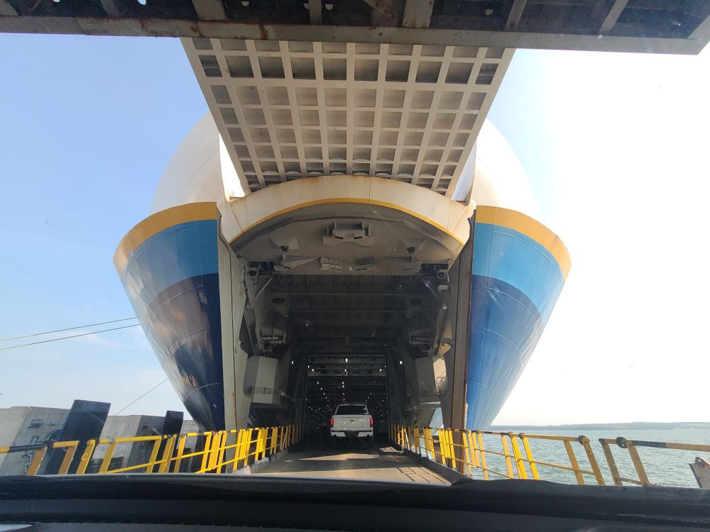 Picture taken through the front window of a car as it's driving across the gangway into a vehicle ferry. 