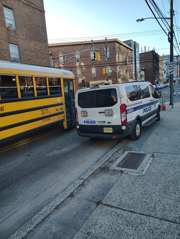 police van parked on the curb, blocking traffic in one direction. a school bus is going into the other lane--which goes the other direction--in order to go forward