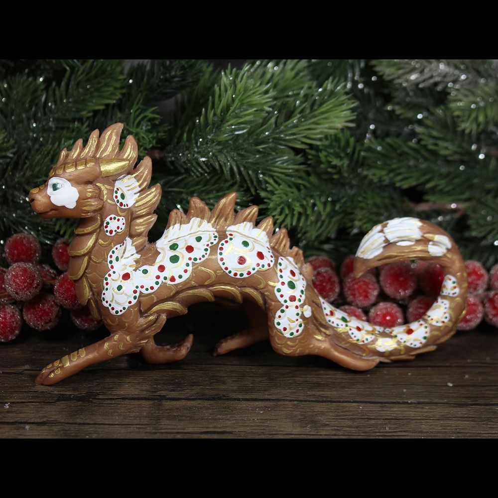 A sculpture of an eastern style dragon, painted like a koi fish.  He is prancing jauntily.  He is gingerbread colored with white "icing" spots, red and green "candies", and accented with metallic gold scales.