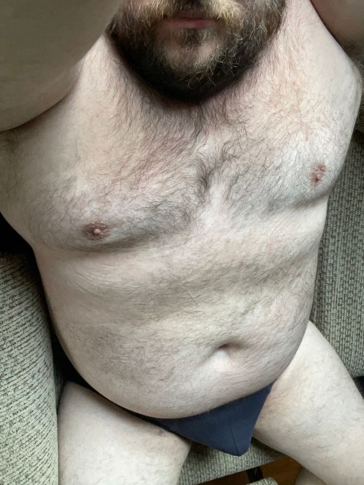 Me in only dark blue briefs sitting on a recliner. Arms raised 