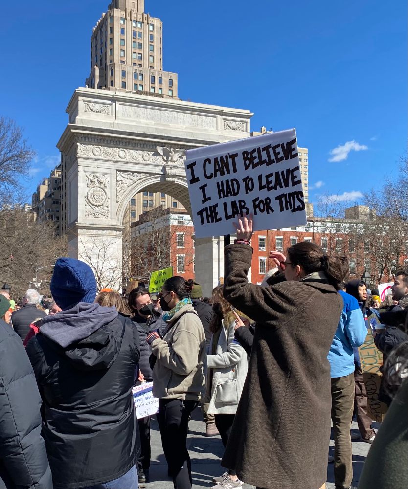 Sign at rally near Washington Square Arch reads I Can’t Believe I Had to Leave the Lab for This 