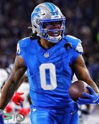 Image of Detroit Lions running back Jahmyr Gibbs in a bright Honolulu blue uniform during an NFL game. Gibbs wears jersey number 0, gripping the football tightly in his right hand while accelerating into the open field. His expression is intense and focused, mouth open mid-play, with his helmet visor reflecting stadium lights. Gibbs’ long dreadlocks flow out the back of his helmet as he runs. The Lions’ uniform is crisp and vibrant — blue jersey, blue pants, silver helmet with the Lions’ roaring-lion logo in metallic detail. His gloves and arm sleeves match the team color scheme, emphasizing Detroit’s visual identity.

Opposing defenders appear blurred in the background, suggesting motion and game-speed intensity. The lighting indicates a primetime or indoor stadium environment. The photo captures Gibbs mid-stride, showcasing his trademark burst, agility, and big-play potential — the qualities that make him such a dangerous real-life and fantasy football weapon.

This image is ideal for content relating to fantasy football, sports betting, and player props because Jahmyr Gibbs is one of the league’s premier dual-threat running backs. Keywords for search and SEO include: Detroit Lions RB Jahmyr Gibbs, NFL Week 11 player props, rushing + receiving yards prop, fantasy football Week 11 picks, DFS running back plays, explosive RB prospects, DraftKings prop bets, PrizePicks rushing/receiving yards, Underdog Fantasy pick’em, FanDuel overs, and BBFF Week Winner projections. This picture reflects Gibbs’ ability to turn a small crease into a chunk gain — the exact reasoning behind recommending his Week 11 prop of over 89.5 total yards and projecting him for 95–115 yards based on matchup data against the Eagles’ defense. The photo visually reinforces his upside: speed, acceleration, contact balance, and home-run playmaking — the traits that make him a weekly ceiling candidate in PPR leagues and prop betting markets.