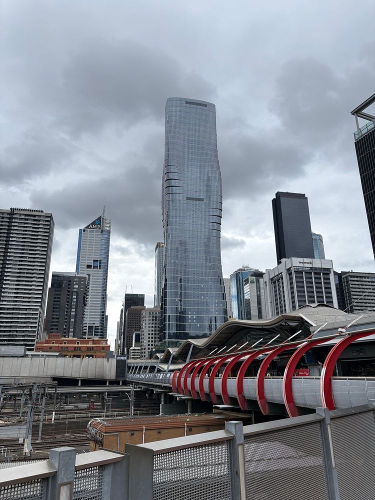 Over the Southern Cross railway station. A walking bridge in the foreground and more tall buildings behind 