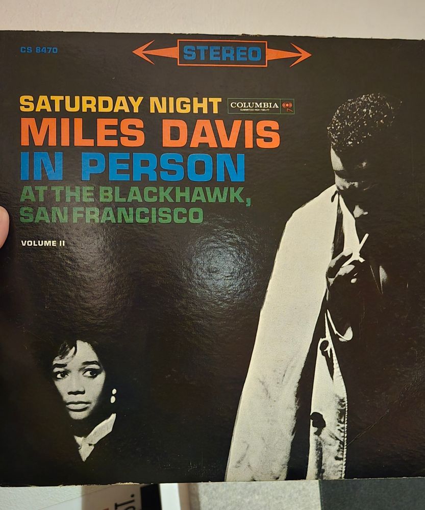 Cover of the album, "Saturday Night Miles Davis In Person at the Blackhawk, San Francisco" Vol II. Cover includes Miles in a trench & Francis Davis, his wife.