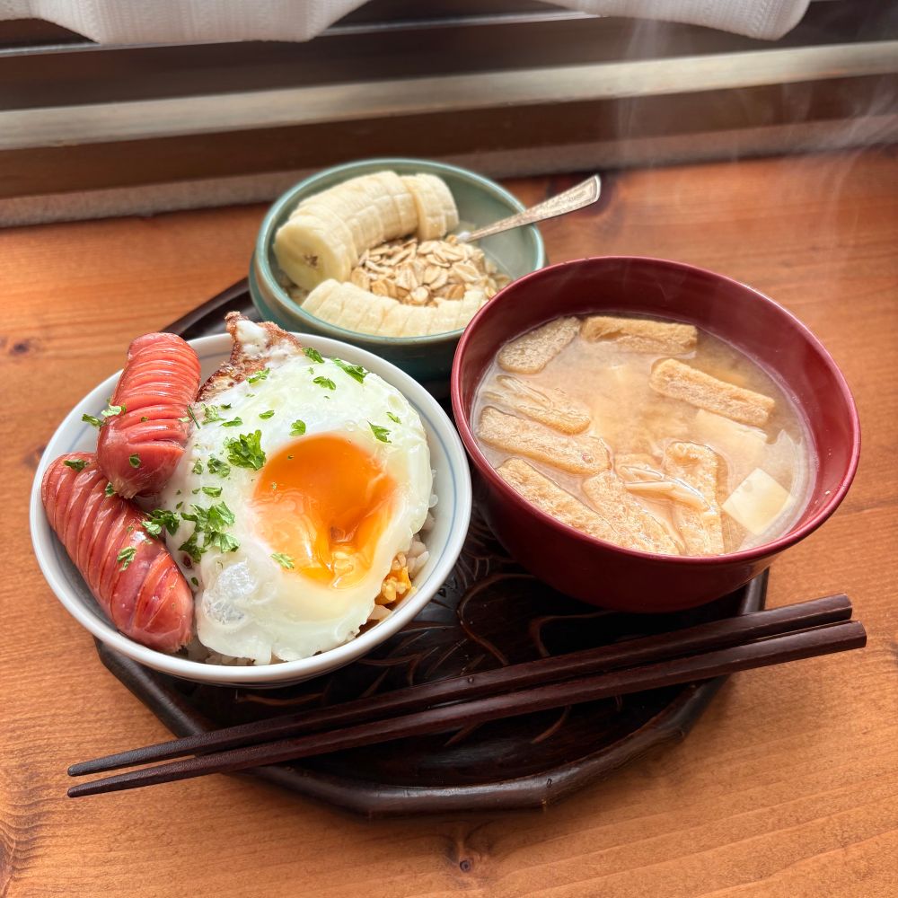 目玉焼き乗っけご飯、ソーセージ、ヨーグルト、オートミール、バナナ、揚げ、豆腐、エノキの味噌汁