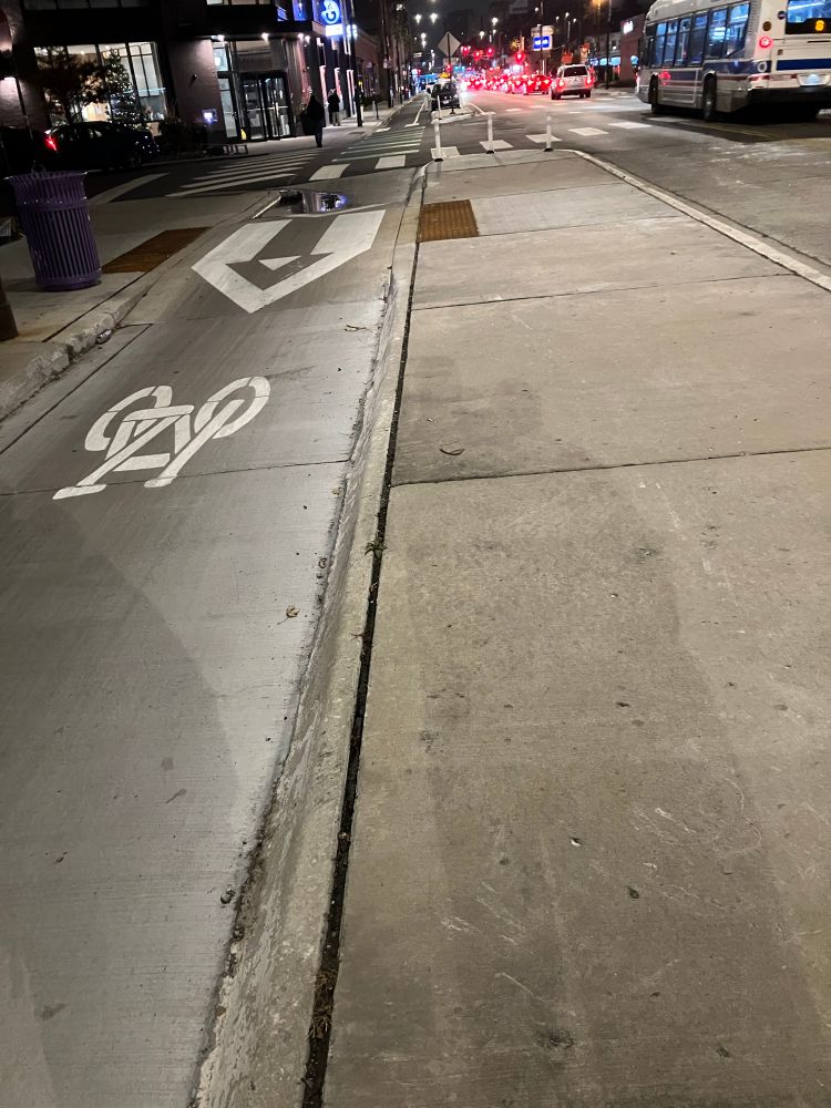 raised pedestrian crossing across a protected bike lane to access a bus stop (not pictured) on a pedestrian island