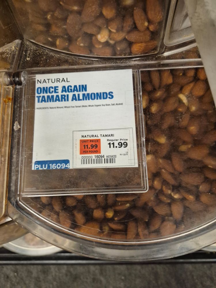 Photo of a bulk bin at a supermarket, the label on which reads "Once Again Tamari Almonds"