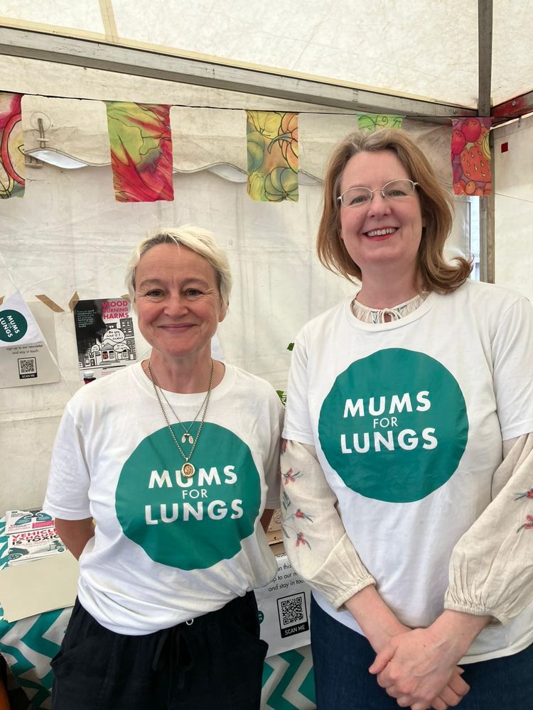 Two people smiling at the camera, wearing white t-shirts with Mums for Lungs logos on them. 