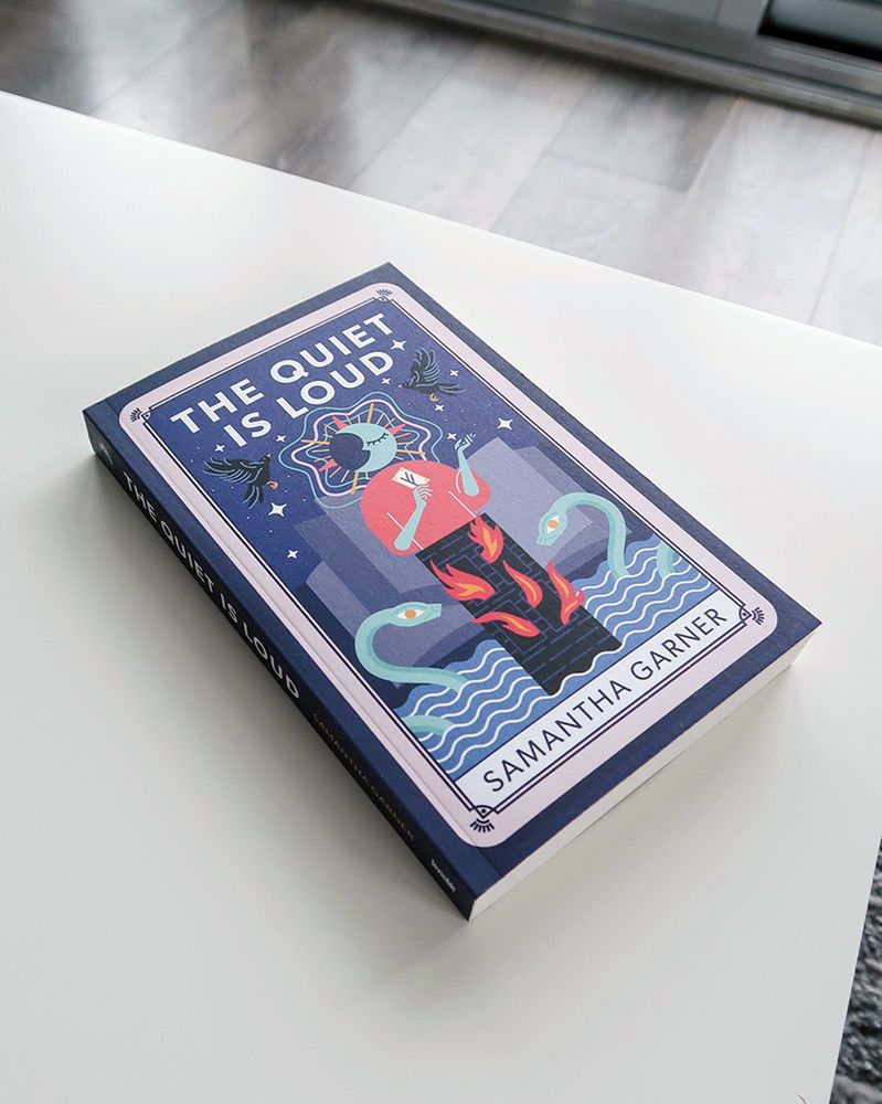 My literary sci-fi novel The Quiet is Loud on a white coffee table.