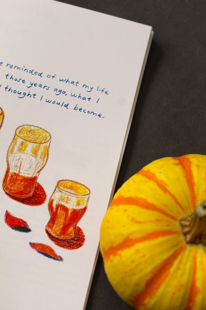 Photo of pumpkin beside a zine page showing artwork of beer in glasses and a fragment of article text.