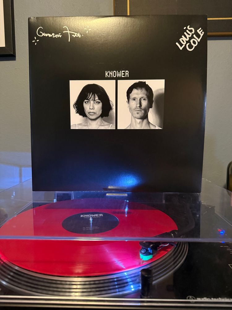 The LP jacket for Knower’s “Knower Forever” sitting on top of a record player with a red LP spinning. 