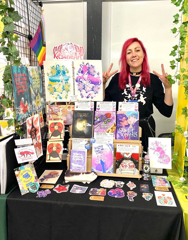 Kitsuneart smiling behind her stall at Thought Bubble 