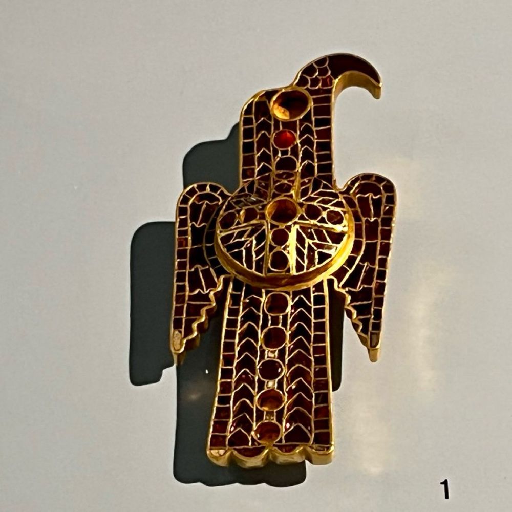 An eagle-shaped brooch made of gold with red stone inlays. 