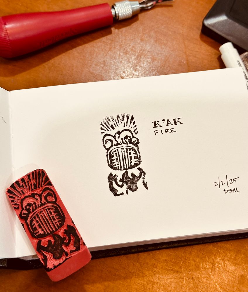 A carved eraser of the Maya glyph for fire (K’ak), with stylized supporting elements, along with a print of that glyph in the post author’s sketchbook.