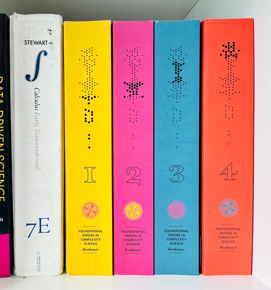 A photograph showing the book spines for Volumes 1 to 4 of Foundational Papers in Complexity Science. 