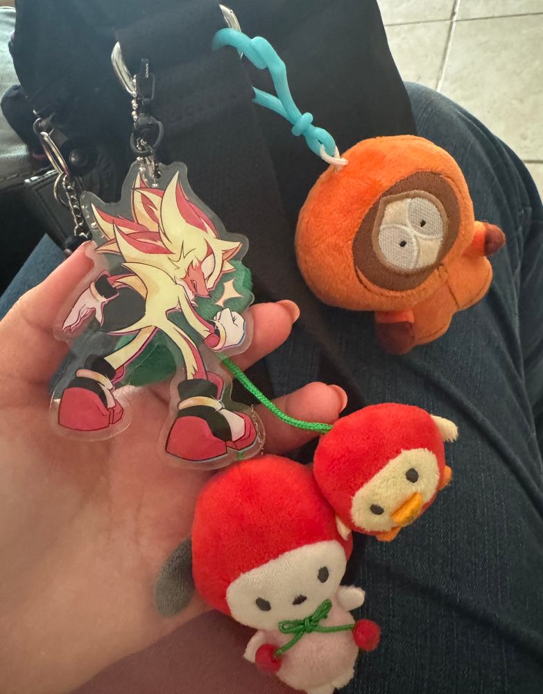 a key chain of shadow the hedgehog in his super form, the sanrio character pochaco and a chicken dressed as cherries, and kenny mccormick from south park