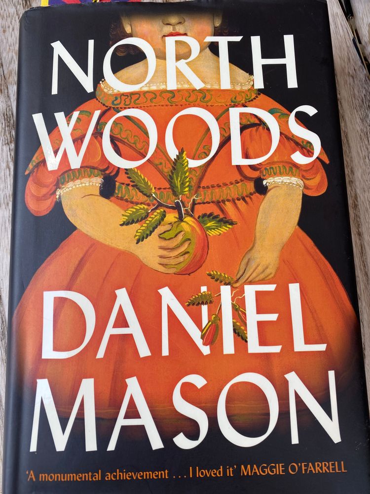 Front cover of Daniel Mason’s ‘North Woods. A woman (maybe Alice or Mary) holding an Apple (presumably an Oshood Wonder)