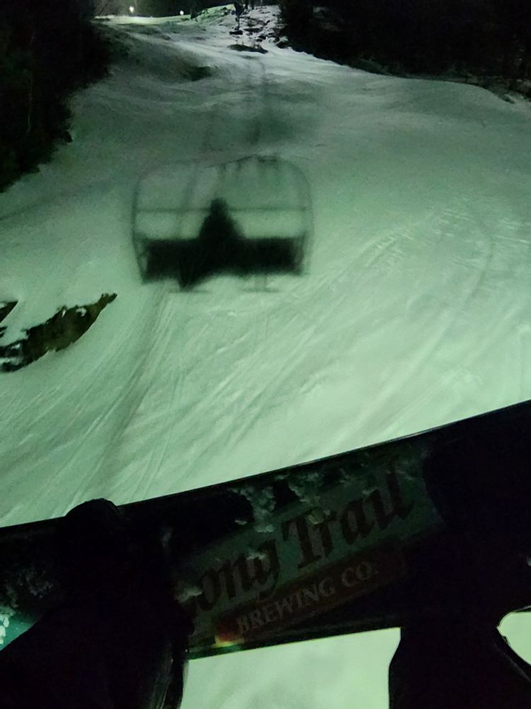 Snowboard on a lift at night.