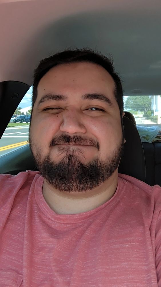 It's me, a pale brown boy, in a red shirt with one eye closed as if winking with my lips pursed tight as I smile, making the infamous "bear face" with a freshly cut set of hair on my head