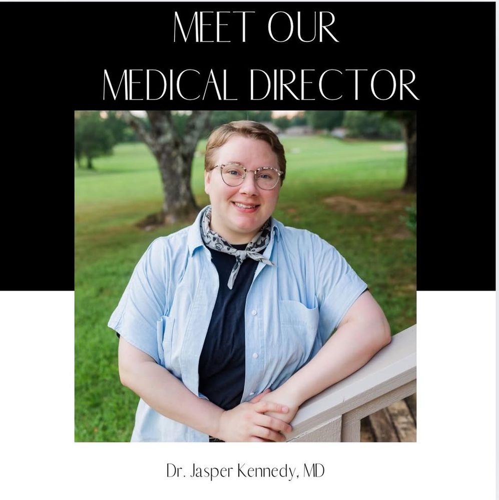 Box divided in two, top half black with white printing reads "Meet our Medical Director" Bottom white with Black print reading "Dr. Jasper Kennedy, MD." in the center of the box is a large picture of Dr. Kennedy, a white person with short blond hair and glasses wearing a light blue short sleeve dress shirt over a black tshirt, with a super jaunty light and dark blue print necktie. While Dr. Kennedy has the sweet face of someone who is posing for their senior picture, I promise they are in fact a licensed medical professional and old enough to have completed residency and NOT a Doogie Howser.
