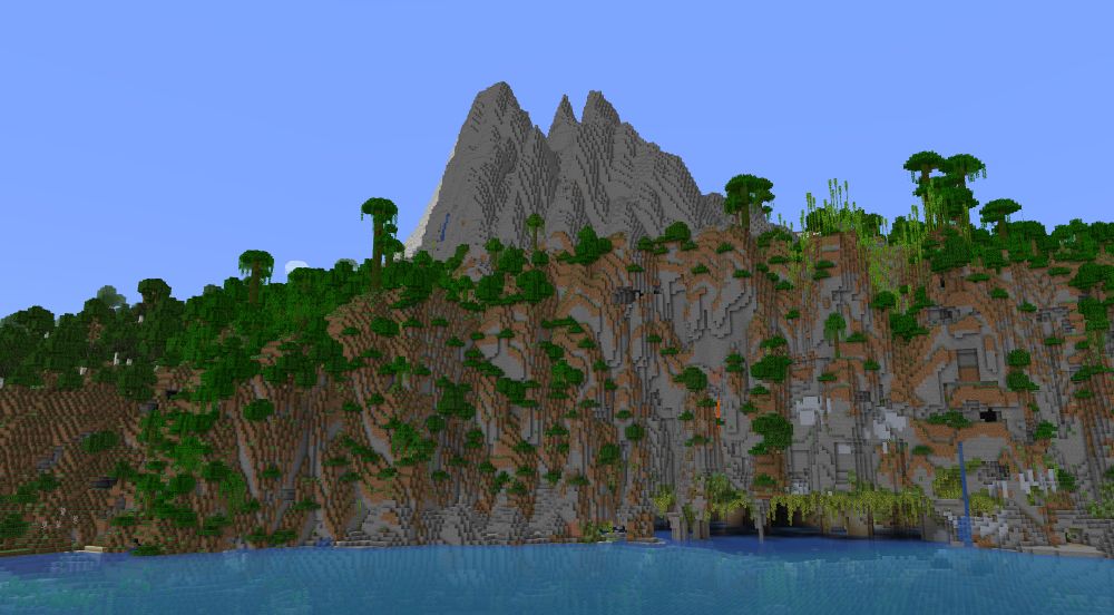 A large seaside cliff of a Jungle biome right in front of some large Stony Peaks. In the cliff is an underground river with Lush Caves peeking through.