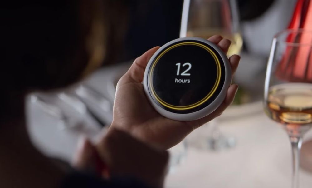 A device that says how long the relationship will last from the hang the dj episode of black mirror, a person has a table with wine staring at the circular device