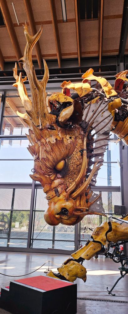 The head of an animatronic dragon, closing its eyes and their head is bent toward the floor