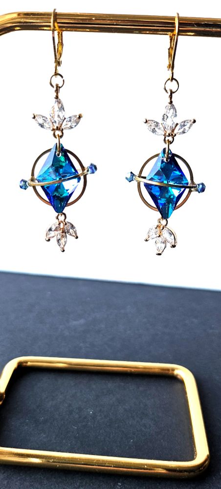 a pair of golden earrings looking like aetherytes with blue crystals and little white crystals inspired from the game final fantasy 14