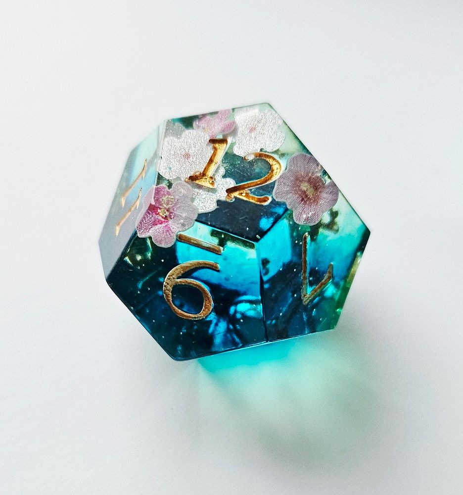 A die blue transparent with pink flowers in it. The numbers are painted in gold. 