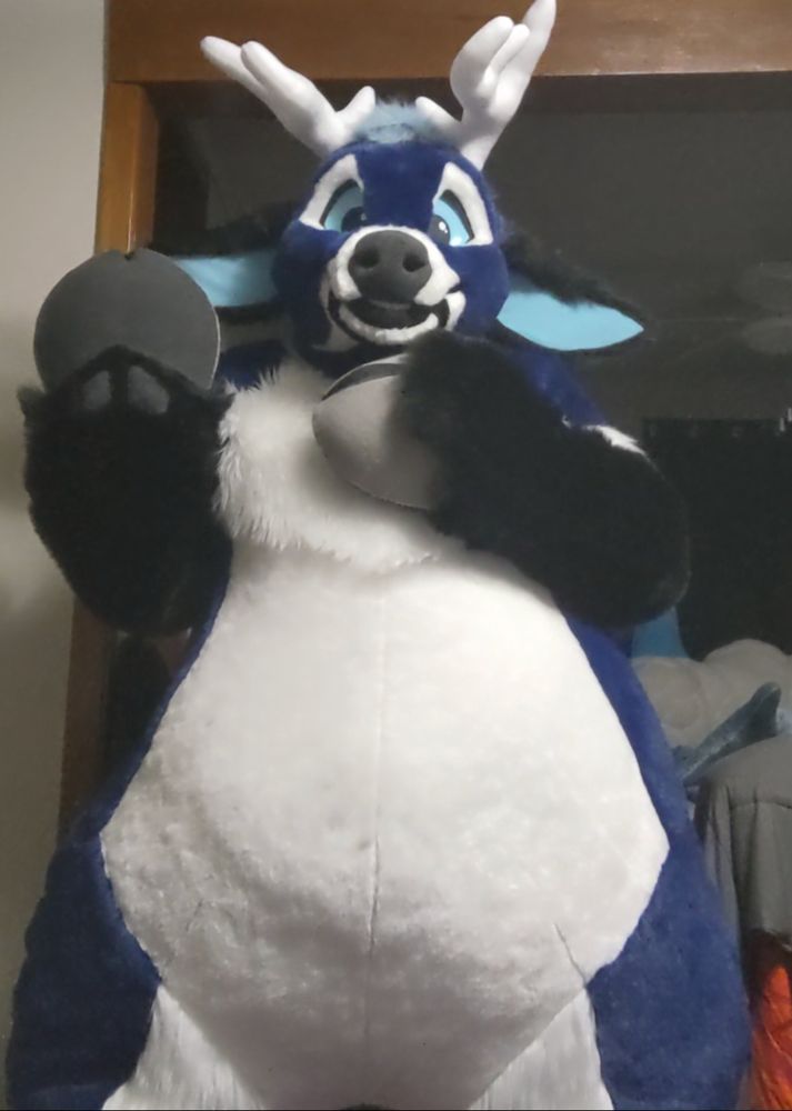 A large blue plush deer fursuit waving hello