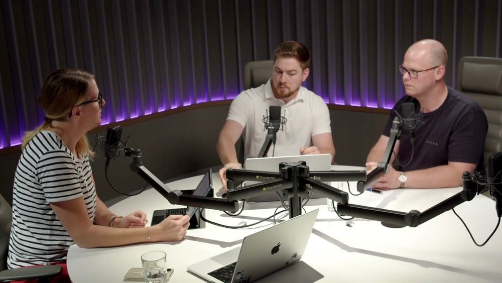 Three people sitting around a round table in a recording studio discussing CARIAD and mobile app development.