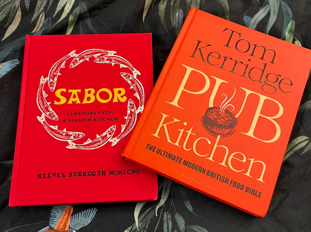 Two cookbooks. Red covered Sabor and orange covered Pub Kitchen. 