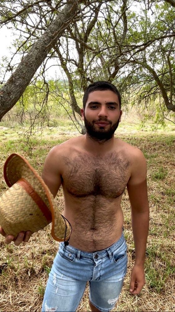 Hombre en el campo con un sombrero en la mano, abanicándose para calmar el calor del verano.