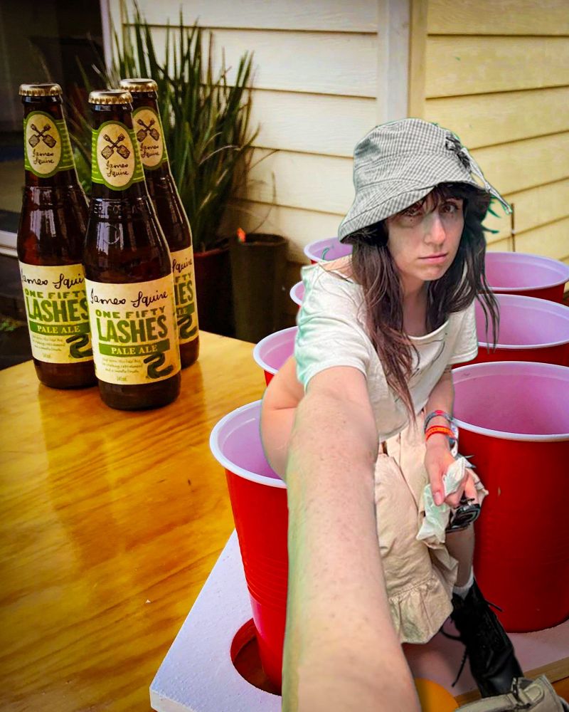 Dodie sits on top of a red solo cup. She is refilling it after losing the last round of beer pong