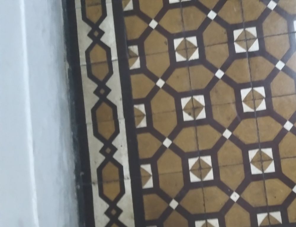 Hermoso piso de baldosa hidráulica en colores ocre, negro y blanco, con guarda lateral simple