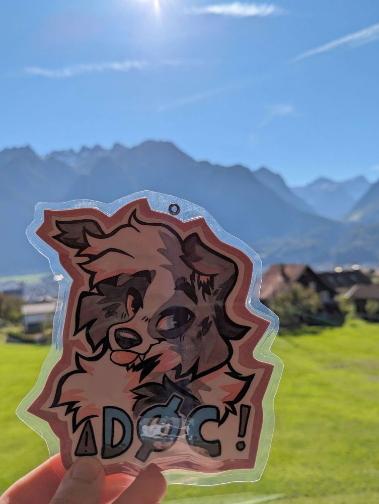 Picture of my badge of my aussie sona in front of mountains.