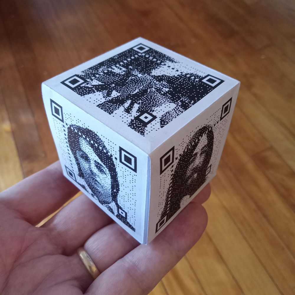An origami cube with QR codes on five of the six faces.
