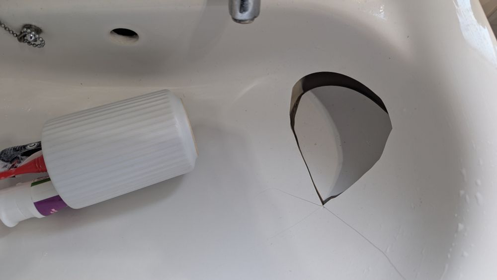A tooth brush holder has fallen into the sink and caused the sink to crack/break leaving a tooth brush holder shaped hole!