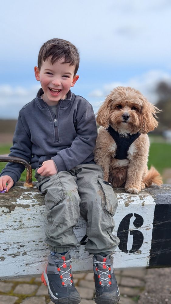 4 year old boy and a small cavapoo sat on a canal lock gate handle 