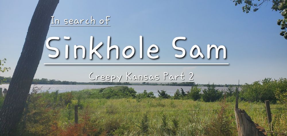 A landscape photograph of Inman Lake near McPherson, Kansas. The lake shimmers under a blue sky. The area around the lake is verdant and wooded, painting a picturesque scene. The title in white text reads, "In search of Sinkhole Sam: Creepy Kansas Part 2". 