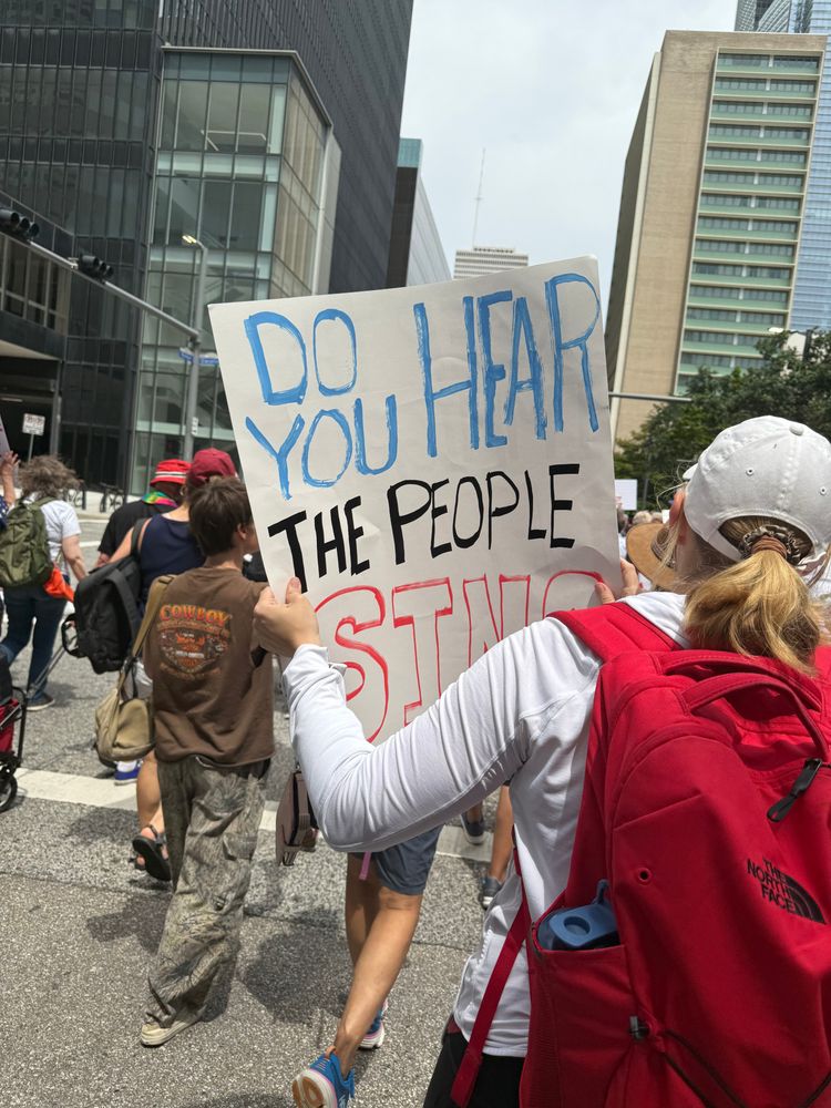 Protest sign reads: Do you hear the people sing?