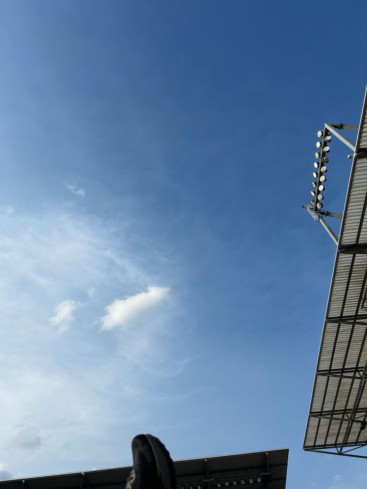 Blauer himmel, am rechten und unteren bildrand beginnt ein Stadiondach aus Wellblech.
