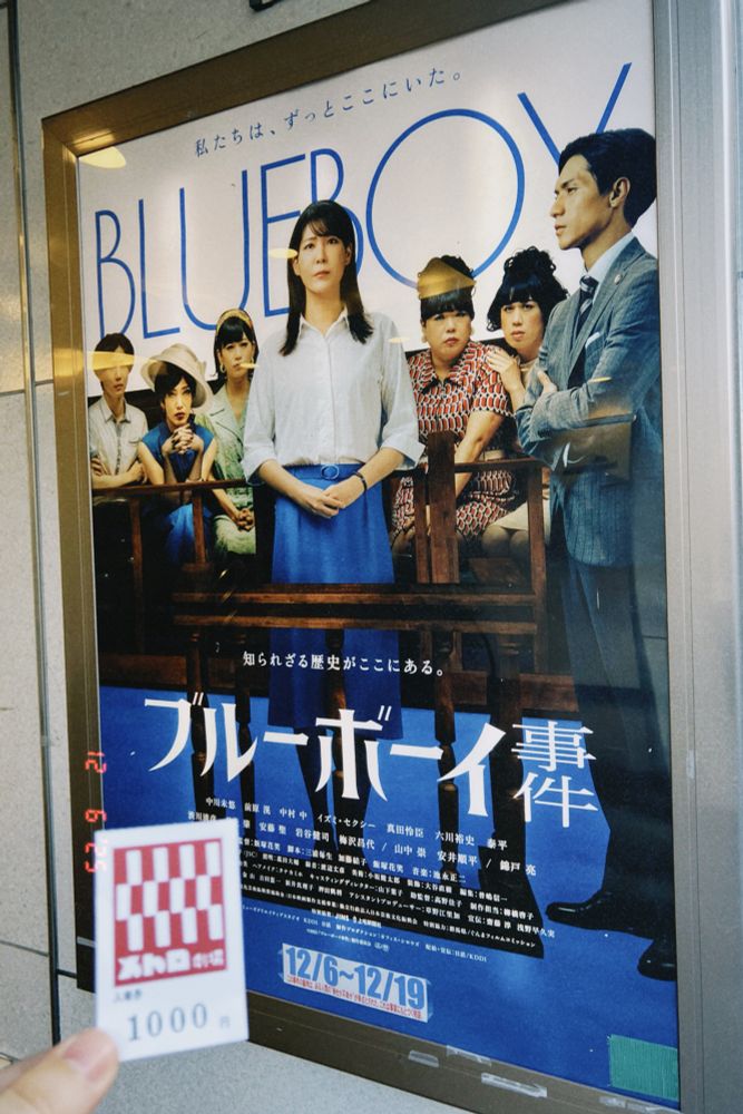 ブルーボーイ事件のポスターの前でメトロ劇場の半券を持っている写真。
