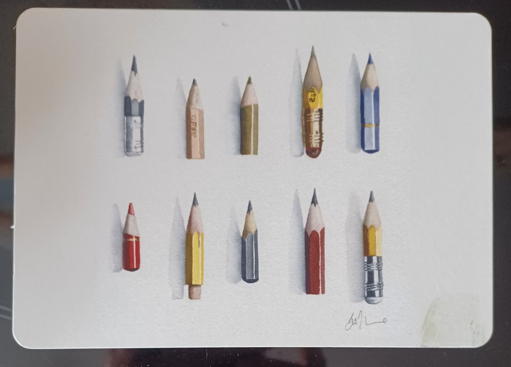 Eine Postkarte mit 10 Buntstiftresten, die extrem weit runter gespitzt wurden, so dass man sie fast nicht mehr greifen kann. 5 in der oberen und 5 in der unteren Reihe. 
Zeichnung einer britischen Künstlerin