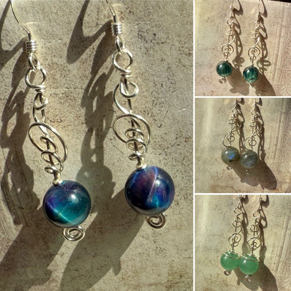 A collage of four pairs of earrings made with round gemstones and swirly silver wire. The stones are dyed tigerseye (blue/purple/teal), green kyanite (deep teal-green), labradorite (greyish-green with blue flash) and aventurine (light green).