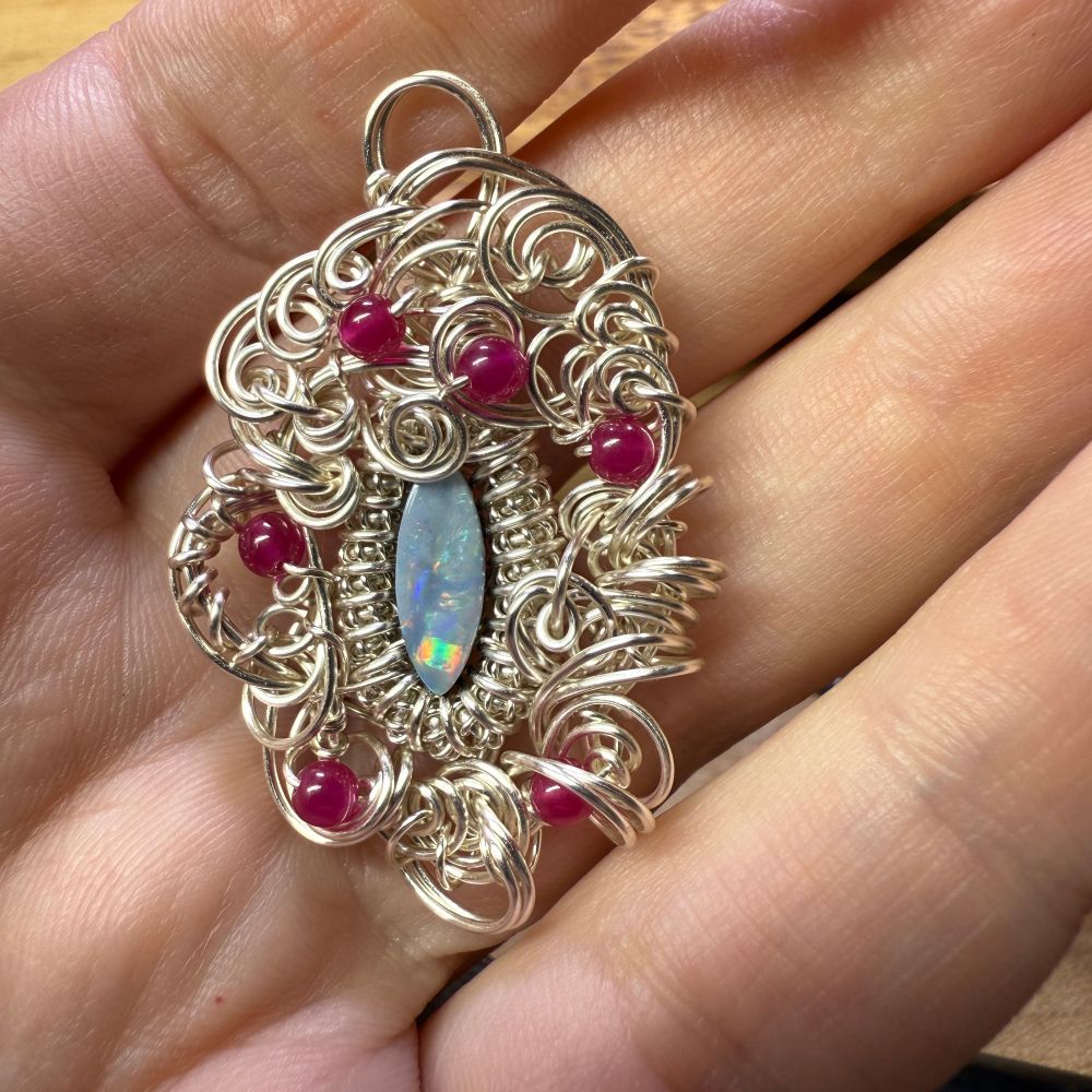 The pendant from the previous skeet, now with about three times as much swirly wirework and half a dozen small red lab-grown rubies for accents. 