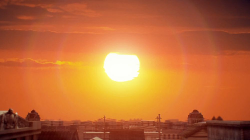 Print do jogo "Raidou Remastered: The Mystery of the Soulless Army". Na imagem se vê um lindo pôr do Sol, o céu bem laranja com o Sol no meio. Na parte inferior da imagem se veem topos de prédios e casas da cidade toda.