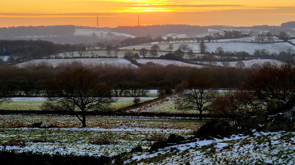Sunset in an orange sky across snowy fields 