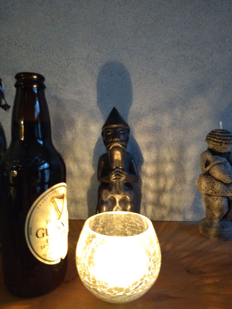 Statuette of Thor, a lit tea light, and offering of Guinness stout 