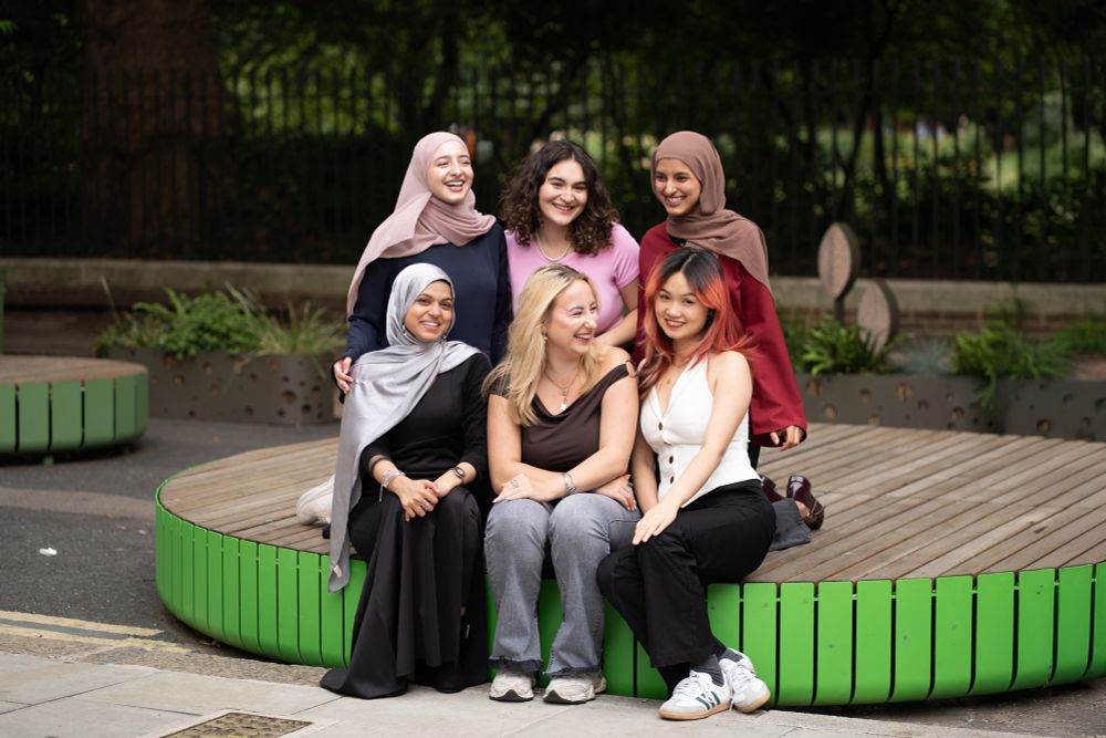 A group photo of the Sabbatical Officers team, smiling and seated on a bench near Gordon Square Park: Anam Choudhary, Students' Union President, Ana Boikova, Activities & Engagement Officer, Sarah Jilani, Education Officer, Hana Mougharbel, Welfare and Community Officer,  Eda Yildirimkaya, Equity & Inclusion Officer and Darcy Lan, Postgraduate Officer.